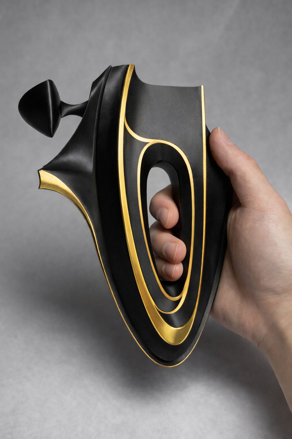 Project Axiom held in one hand, showing the integrated grip cavity and gold edge accents