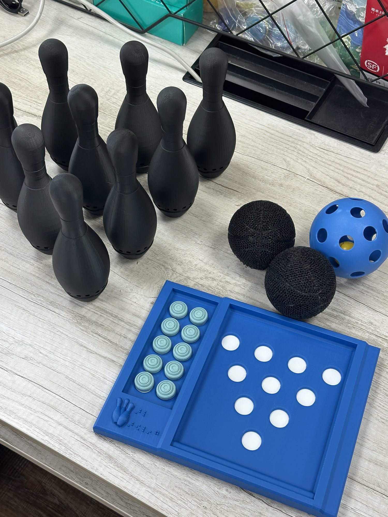 Bowling pins, audio balls, and tactile game board developed for blind and low-vision sports
