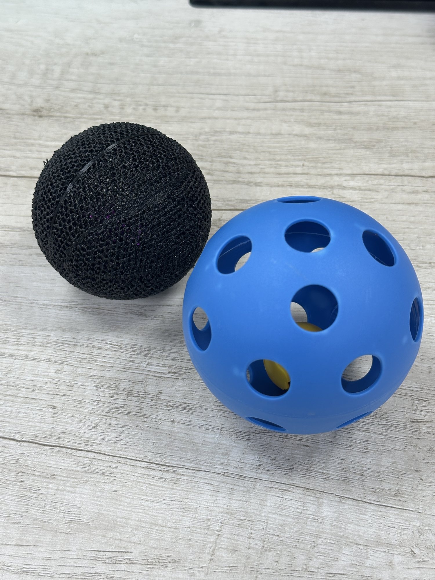 Flexible black audio bowling ball beside an earlier perforated blue shell