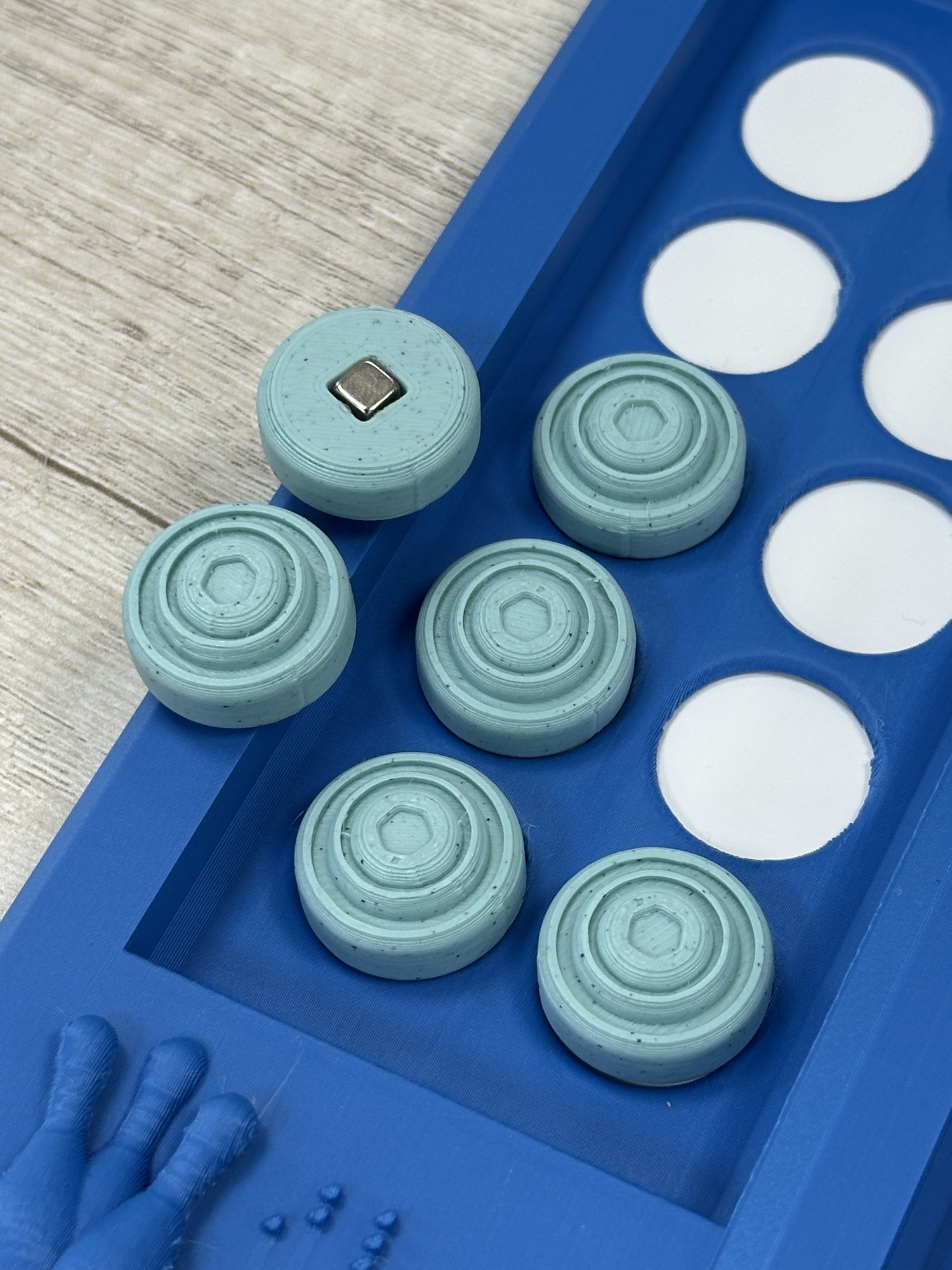 Magnetic tactile markers and Braille details on the blue game board