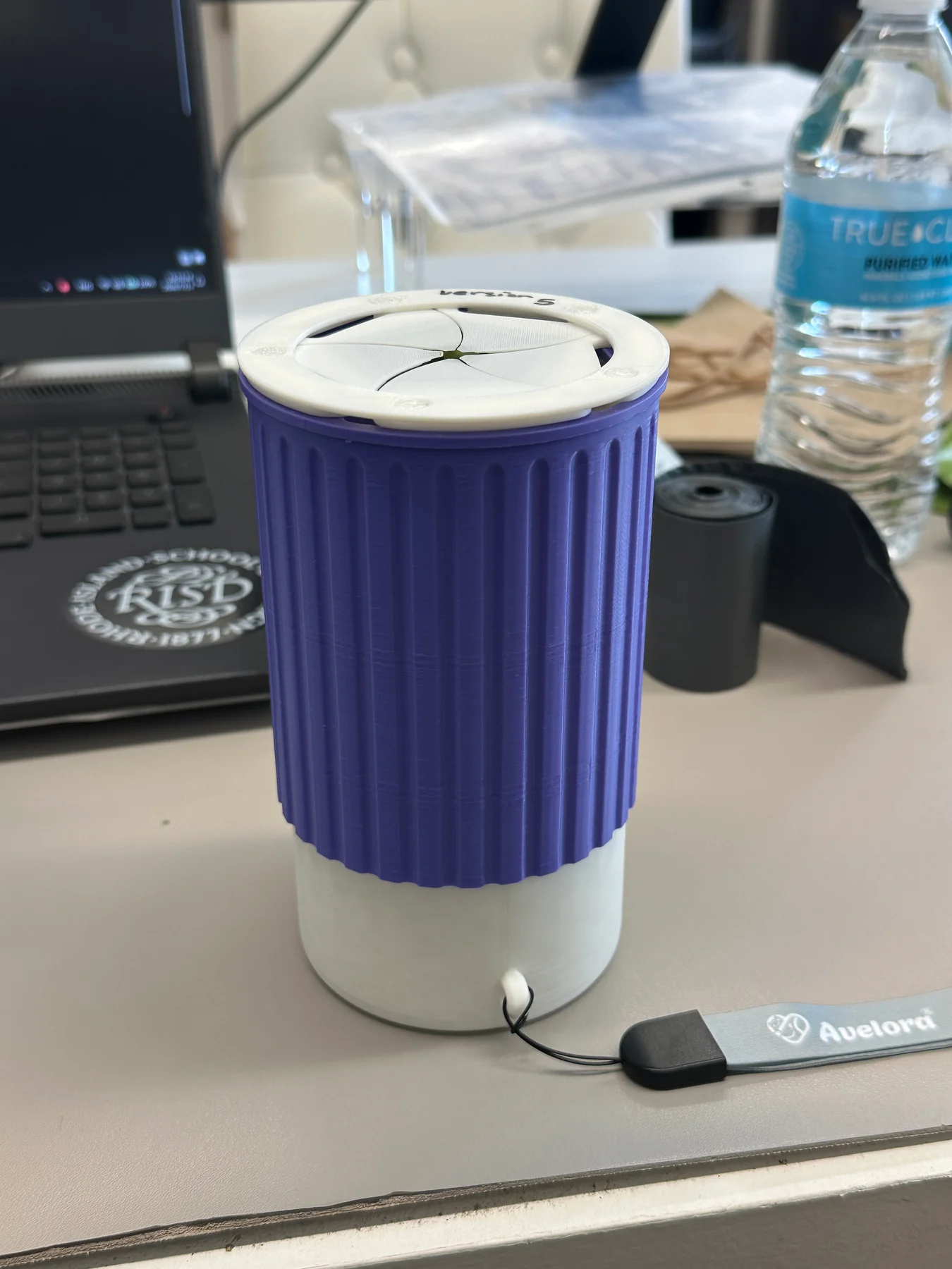 Latest purple-and-white printed prototype with ribbed outer sleeve, iris opening, lower compartment, and attached wrist strap